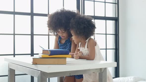 Two African American little girls enjoy to play together as teacher and student