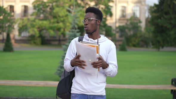 Young Handsome African American Man in Eyeglasses Standing Outdoors with Paperwork Waiting