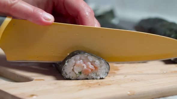 The Chef Cuts Sushi and Rolls Made From Seafood with Asian Ingredients with a Knife