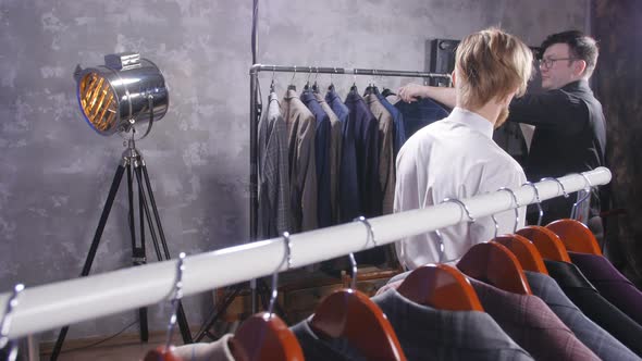 The Seller Helps a Young Elegant Man To Choose a Classic Suit in the Store