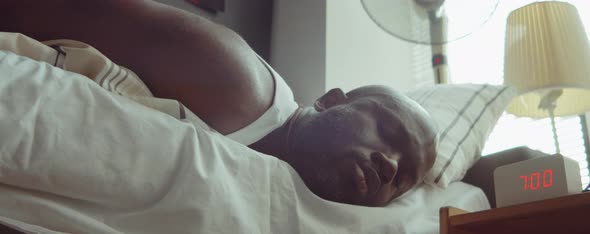 African American Man Turning Off Alarm Clock after Waking Up