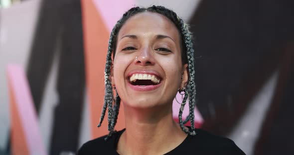 Trendy young woman with braided hair laughing on camera