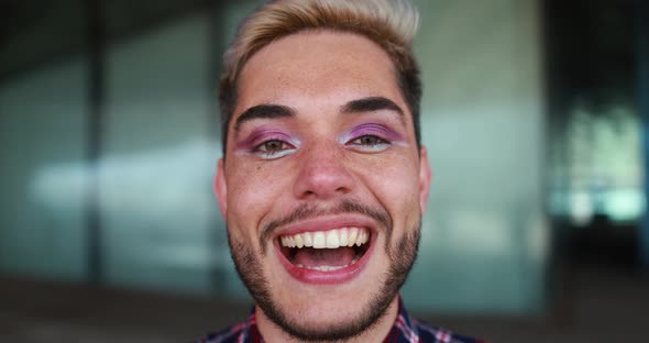 Young transgender man with makeup laughing on camera outdoor
