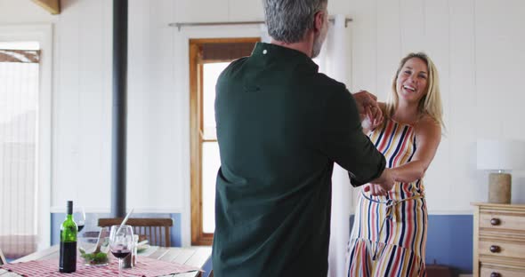 Happy caucasian mature couple dancing in the sunny living room