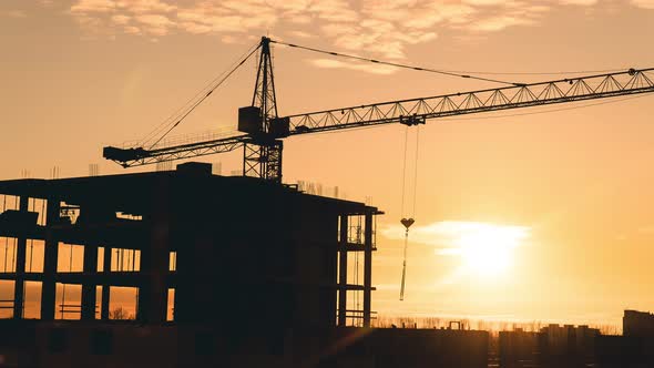 Timelapse of a working construction crane against the backdrop of a beautiful sunset sky.