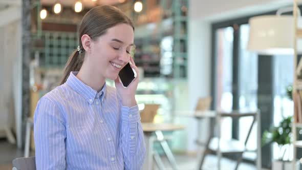 Young Businesswoman Talking on Smartphone in Cafe
