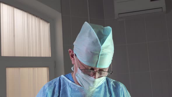 Closeup of a Surgeon During an Operation Looks at the Camera and Approvingly Nods