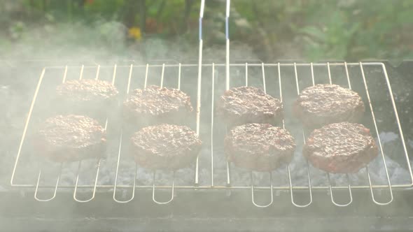 Chef Cooks burger in street outdoors. Summer Picnic in Nature. Tasty Meat Dish