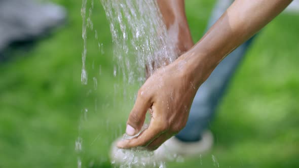 Closeup African American Male Hands Washing with Water Outdoors on Sunny Day