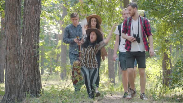 Group of Cheerful Young Friends Hiking on Sunny Summer Day Outdoors As Beautiful Caucasian Woman