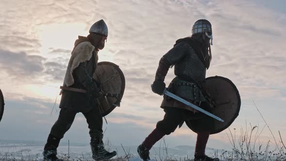 Group of Medieval Vikings with Arms and Shields Going on the Winter Meadow.