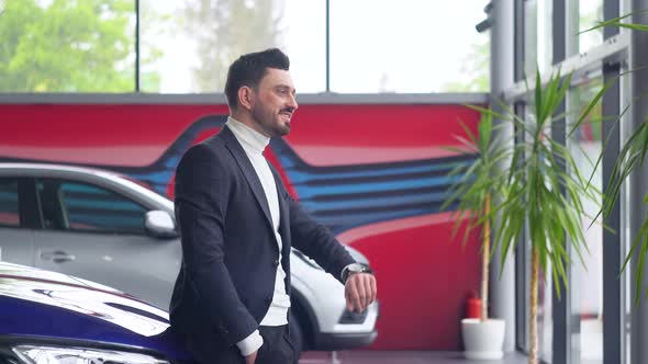 Elegant Man Uses a Smart Watch in Car Showroom