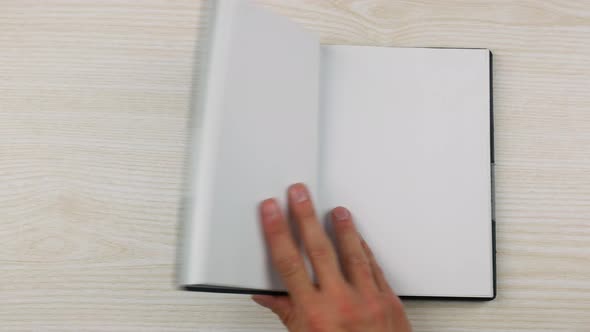 The Hand of a Businessman Puts and Opens an Empty Diary on the Table