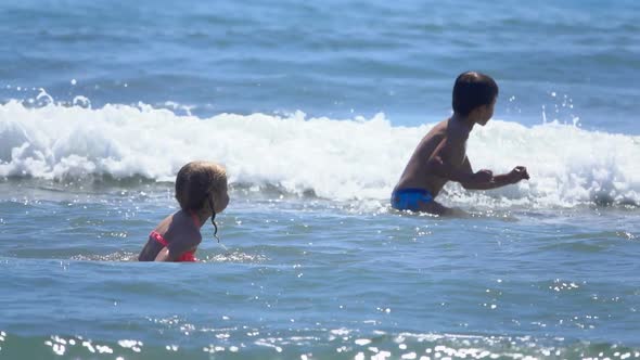 Little Happy Children Are Jumping in Splashing Sea Waves on the Beach