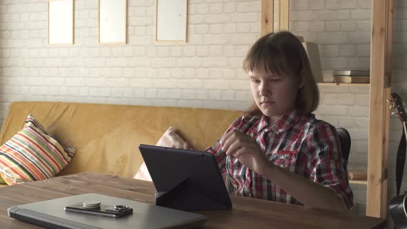 Teen Girl Communicates With Laptop At Home By Window At Wooden Table