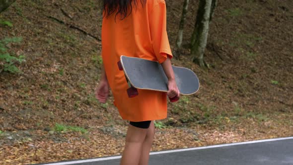 Young Woman with Skateboard in Hands is Walking Outdoors Sporty Hobby