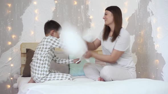 A Girl and a Little Boy are Having Fun Hitting Each Other with Paddles Sitting on the Bed