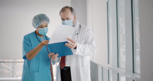 Doctor Explaining Patient Diagnosis To Nurse Wearing Protection Mask