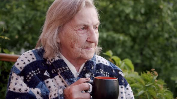 Portrait of an Elderly Woman an Old Granny Standing with a Mug of Tea Looking Into the Distance with