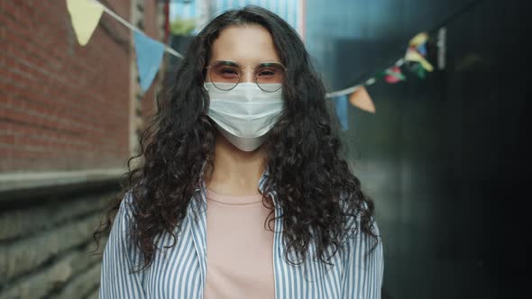 Slow Motion Portrait of Young Asian Lady Wearing Medical Face Mask Standing Outdoors Alone