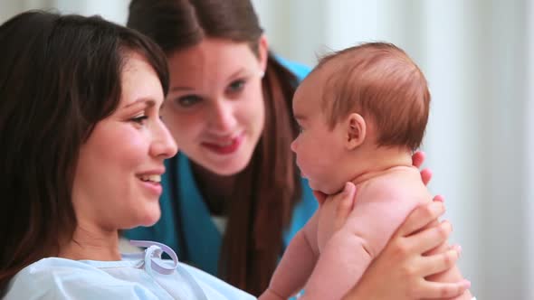 Woman holding her baby next to a nurse