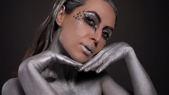 Portrait of a Female Model with Silver Skin and Makeup on a Black Background