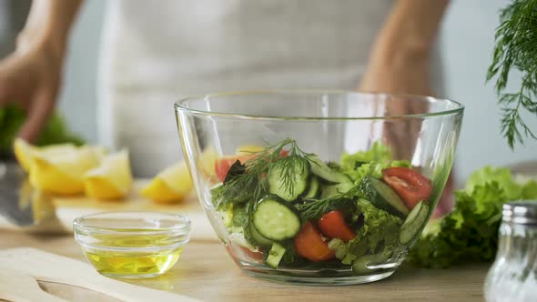 Closeup of Female Chef Hands Squeezing Fresh Lemon Juice Into Bowl with Salad