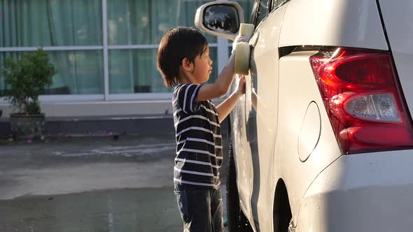 Asian Child Washing Car In The Garden On Summer Day Slow Motion