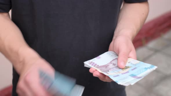 Man Holds in Hands and Counting New Ukrainian One Thousands Hryvnias Banknotes