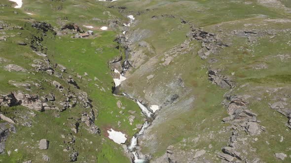 Aerial: drone flying over scenic high waterfall, mountain stream falling from tall rocky cliff
