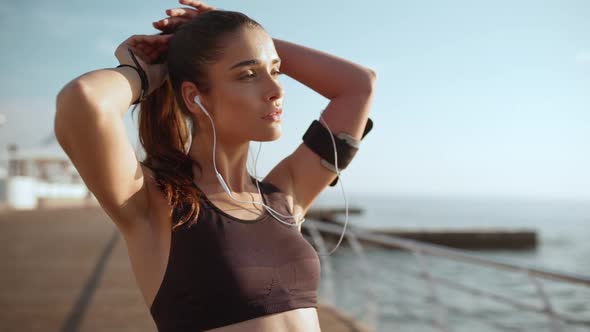 Young Beautiful Sportive Girl Resting Listening Music in Headphones at Seaside