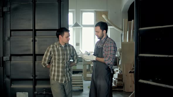 Two Woodworkers in Factory Discussing in About Something.