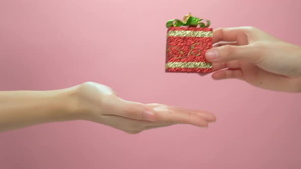 Woman hand hold box gift and send to friends on the pink background.