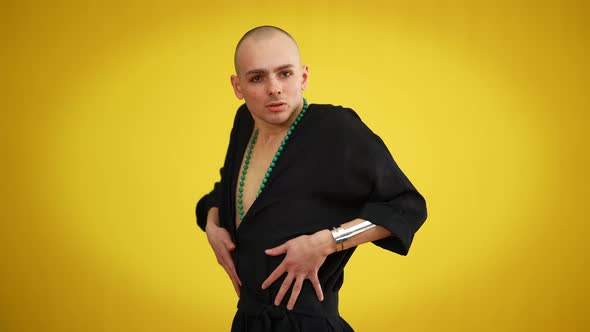 Portrait of Young Male Queer in Black Elegant Dress and Necklace Posing at Yellow Background