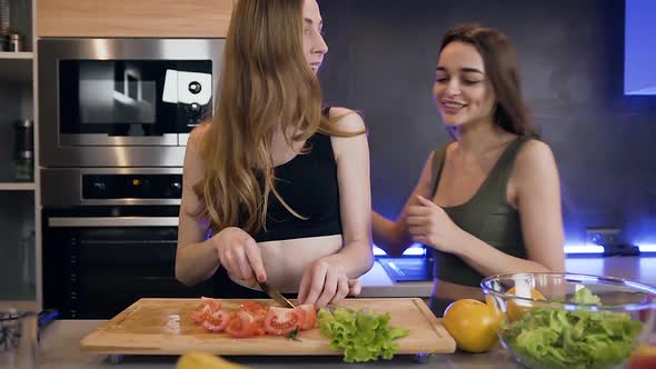 Slender Young Women which Having Fun Together while Preparing Fresh Vegetable Salad