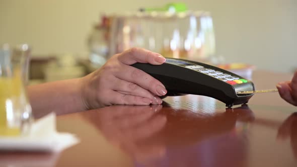 Close-up of female hands holding a terminal in a cafe, restaurant, store