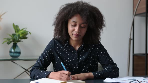 Smart Confident Darkskinned Student Girl Dressed in a Stylish Shirt Sits at Her Desk with a Notebook