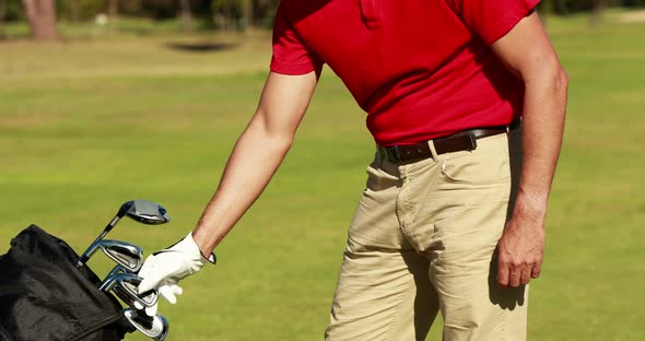 Male golfer removing golf club from golf bag