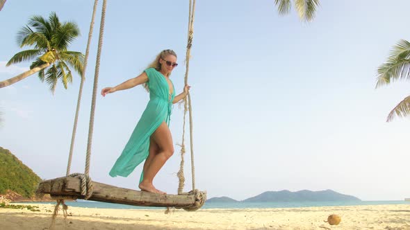 Woman Swinging on a Swing on a Tropical Beach on Shores of the Turquoise Sea