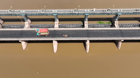 An aerial view of a beautiful bridge on the river. Cars and lorry are seen going through the bridge