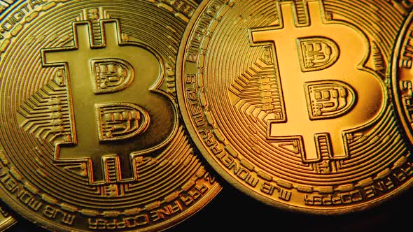 Close-up of a Bitcoin cryptocurrency coin with beautiful highlights of yellow light. Camera movement