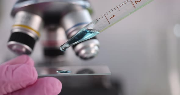 Scientist Chemist Dripping Blue Drops on Glass in Front of Microscope Closeup  Movie Slow Motion