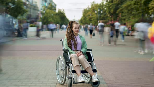 Zoomin Time Lapse of Attractive Disabled Girl with Dreads Hairdo Sitting in Wheelchair in Busy