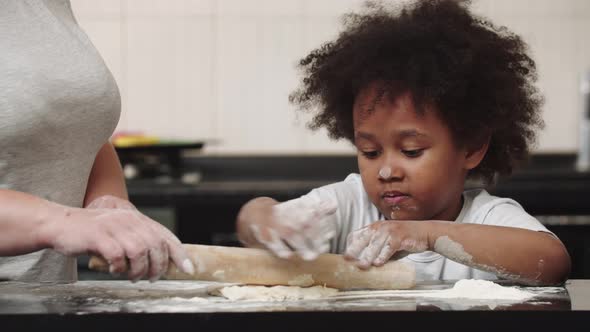 Black Little Girl with Her Mother Making Dough in the Bright Kitchen