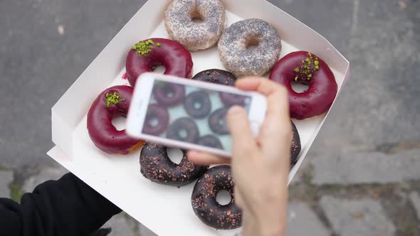 Top View of Taking Pictures of a Dozen Organic Vegan Donuts on a Smartphone