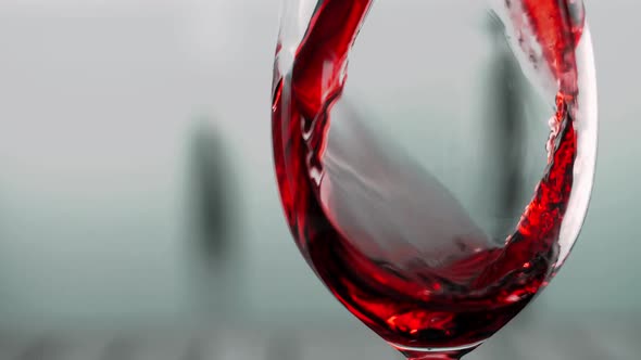 Red wine is poured into a glass, forming a beautiful wave
