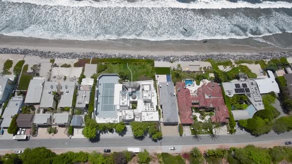 Drone flying over houses, beach and ocean waves in Malibu, California, USA