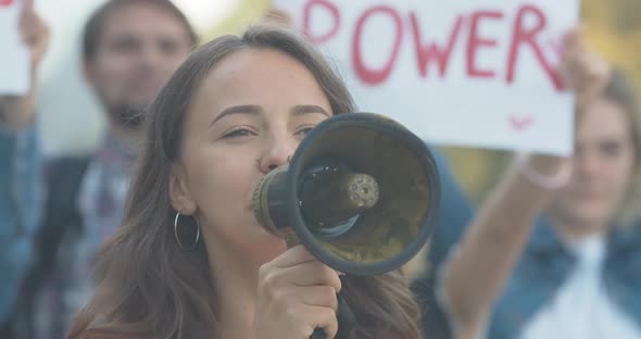 Close-up of Young Caucasian Feminist Shouting Through Megaphone. Protest Leader Encouraging