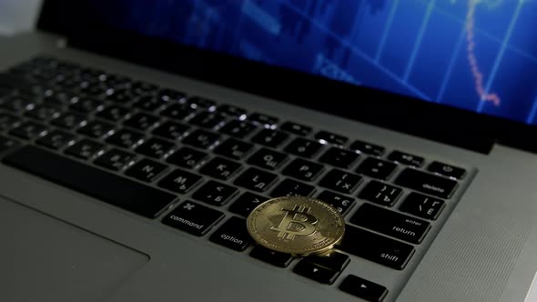 Dolly shot of Bitcoin BTC cryptocurrency. Golden coin on laptop keyboard, slow motion