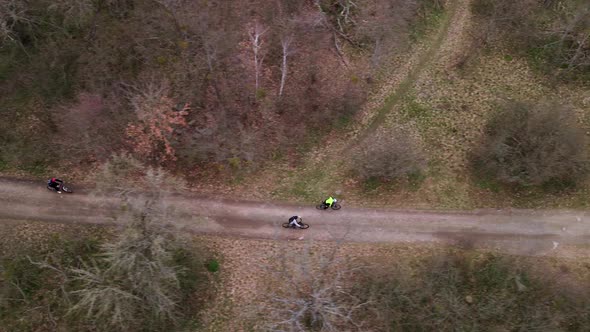 Aerial Top Down Shot of Young Sport Men Ride Bicycles on Countryside Road at Spring Cloudy Day